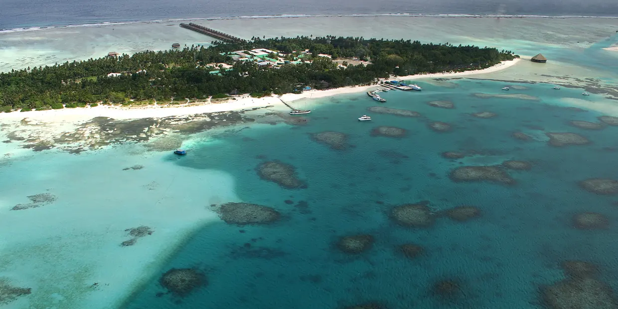 A Maldivian resort island ringed by reef and shallow water