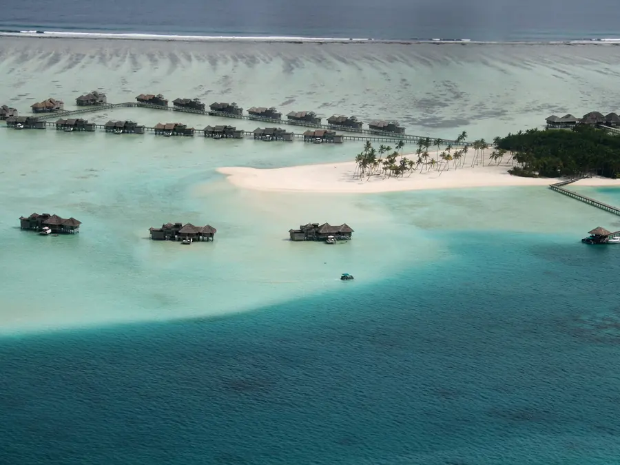 Overwater villas on a turquoise Maldivian lagoon, from the air